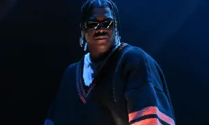 Lil Yachty w Polsce, w okularach i z długimi kolczykami, w swetrze z czerwonymi pasami.