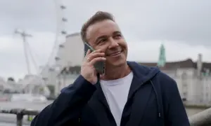 Uśmiechnięty mężczyzna rozmawia przez telefon. W tle widać London Eye. Weekend, halo, tu Londyn!