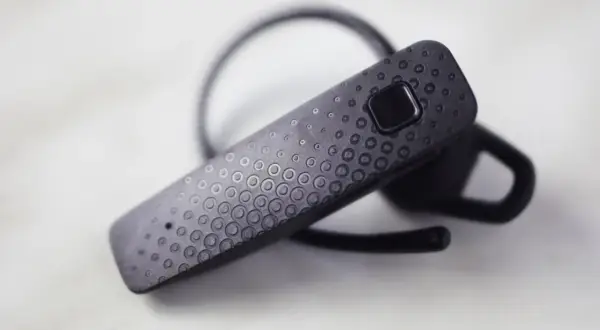 Czarna słuchawka Bluetooth F9 z teksturowaną powierzchnią i przyciskiem.