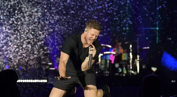 Imagine Dragons wokalista Dan Reynolds śpiewa z pasją na scenie, otoczony konfetti.